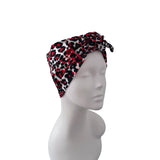 A red, black, and white leopard print knotted headwrap displayed on a white mannequin head against a plain white background.