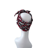A red, black, and white leopard print headband tied in a bow on a white mannequin head, shown against a plain white background.