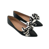 Black pointed-toe flats with zebra-patterned bows on a white background