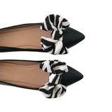 Black flats with zebra print bows on a white background