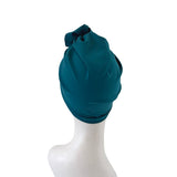 Teal headscarf on a mannequin head against a white background
