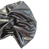 A close-up of a gathered, metallic silver fabric accessory, likely a scrunchie or hair tie, showing its shiny, reflective texture against a plain white background.