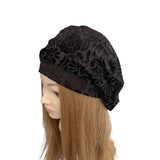 Black floral-patterned headscarf on a mannequin head with brown hair against a white background