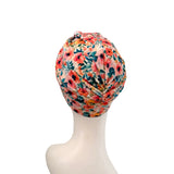 A floral turban-style headwrap displayed on a white mannequin head against a plain white background.