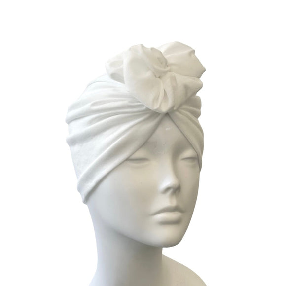 White turban with floral detail on a mannequin head against a white background