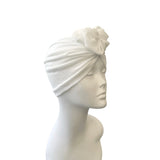 White turban with a flower on a mannequin head against a white background