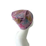 Pink headscarf with butterfly patterns on a mannequin head against a white background