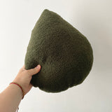 Hand holding a green textured pillow against a plain background