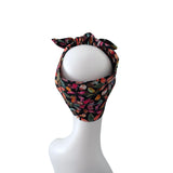 A multicolor floral headband with a bow, displayed on a white mannequin head against a solid white background.