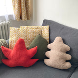 Decorative pillows on a gray sofa with a patterned curtain in the background