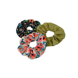 Three scrunchies with floral and solid designs on a white background