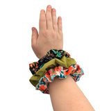 Hand wearing three colorful scrunchies on a white background ireland