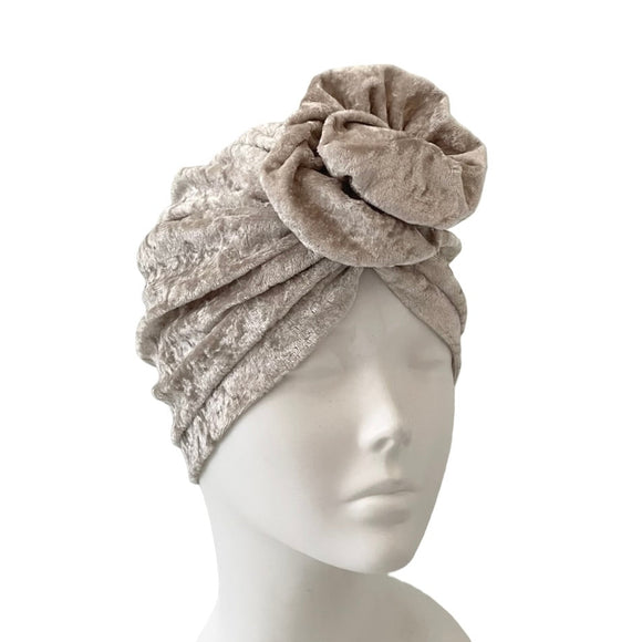 beige headscarf with floral embellishments on a mannequin head against a white background