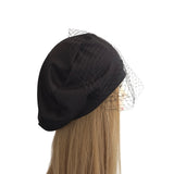 Black beret with a veil on a mannequin head against a white background