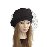 Black hat with a netting veil on a mannequin head against a white background