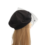 Black beret with a mesh veil on a mannequin head against a white background