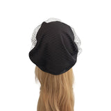 Black beret with a veil on a mannequin head against a white background