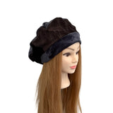 Black velvet beret on a mannequin head with brown hair against a white background