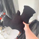 Black sherpa bat held by a hand against a Halloween-themed background with decorations.