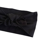 A close-up of a black fabric headband with a knotted bow detail, shown against a plain white background.