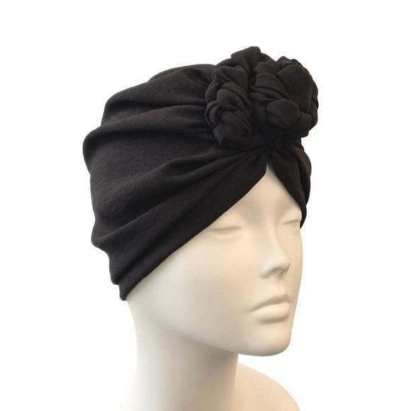 Black headscarf with a flower on a mannequin head against a white background