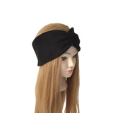 A black twisted headband displayed on a mannequin head with long light brown hair, set against a plain white background.