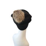 Black beanie with a fur pom-pom on a mannequin head against a white background