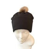 Black beanie with a brown pom-pom on a mannequin head against a white background