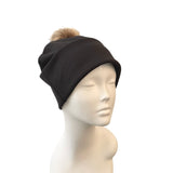 Black headband with a pom-pom on a mannequin head against a white background