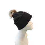Black beanie with a pom-pom on a mannequin head against a white background