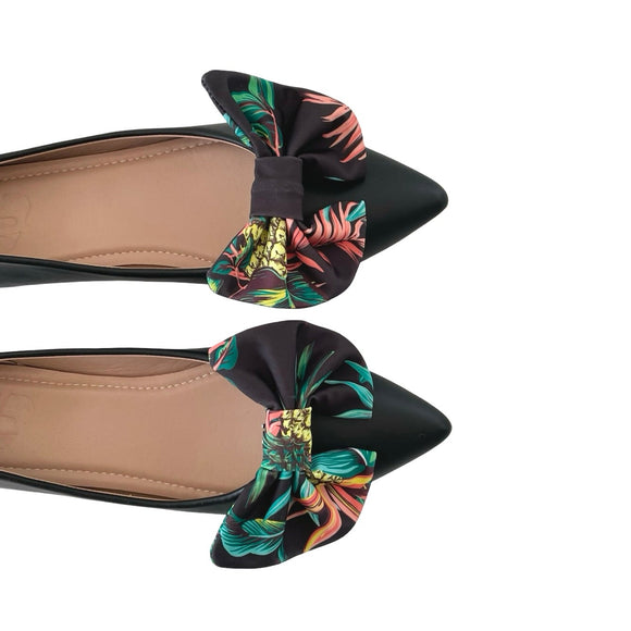 Black flats with colorful floral bows on a white background