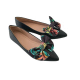 Black pointed-toe flats with floral bow details on a white background