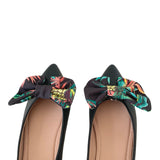 Black shoes with colorful floral bows on a white background