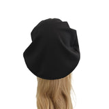 Black beret on a mannequin head with blonde hair against a white background