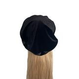 Black beret on a mannequin head with blonde hair against a white background