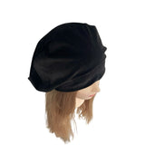 Black beret on a mannequin head with brown hair against a white background