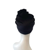Black turban on a white mannequin head against a white background