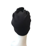 Black turban on a white mannequin head against a white background