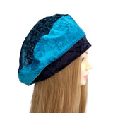 Blue and black beret on a mannequin head with long hair against a white background