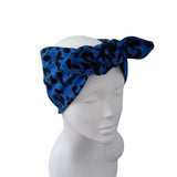 A blue and black leopard print headband with a large bow, displayed on a white mannequin head against a plain white background.