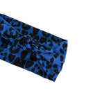 A blue fabric headband with a black leopard print pattern, styled in a knot on a plain white background.
