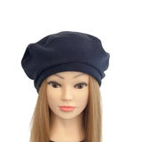 Mannequin head with long blonde hair wearing a navy blue beret on a white background
