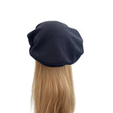 Navy blue beret on a mannequin head with blonde hair against a white background
