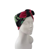 A multicolor patterned headwrap turban hat with red, green, and black sections, styled on a white mannequin head against a plain white background.