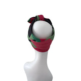 A multicolor patterned fabric headband with a bow, displayed on a white mannequin head against a plain white background.