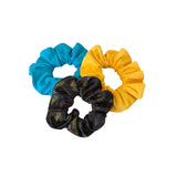 Three scrunchies in blue, yellow, and black with feather pattern on a white background