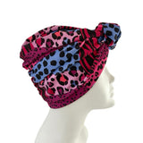 Turban with pink and blue leopard print pattern on a mannequin head against a white background