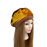 Mannequin head with a yellow and brown headscarf on a white background