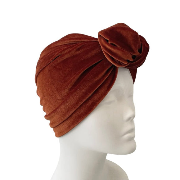 rust turban with a decorative knot on a mannequin head against a white background