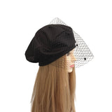 Black beret with a mesh veil on a mannequin head against a white background